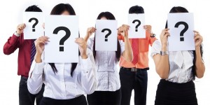 Colleagues holding question mark signs in front of their faces