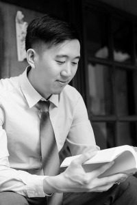 Asian Man Reading a Book Sitting on Bench